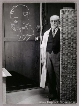 Henri Matisse staat tegen een scherm en tekent met krijt Henri Matisse staat tegen een scherm en tekent met krijt