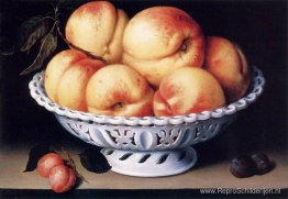 Witte keramische kom met perziken en rode en blauwe pruimen Witte keramische kom met perziken en rode en blauwe pruimen